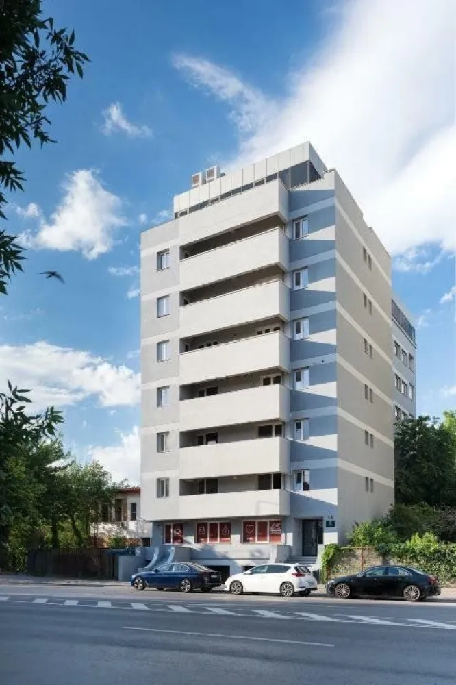 Apartament premium Mozart Residence - Reședința Mozart, amplasată la etajul 4 și beneficiind de priveliști panoramice asupra Bucureștiului, îmbină armonios eleganța contemporană cu confortul exclusivist. Acest apartament luxos, situat pe un întreg etaj, reprezintă alegerea perfectă pentru cei care își doresc un stil de viață modern și sofisticat, având acces rapid la toate facilitățile pe care le oferă orașul.
Imobilul este situat la 1.5 kilometri de Piața Universității, in apropierea Operei Naționale Române si cu acces direct in parcul Facultății de Drept. Imobilul a fost construit in 1994 și refăcut complet in 2024 inclusiv exteriorul, parcarea, și toate instalațiile.
Mozart Residence are vederi panoramice unice ale Bucureștiului către Facultatea de Drept, Opera Națională, Palatul Parlamentului, Catedrala Mântuirii Neamului, Palatul CEC, și Grand Hotel București (fostul Intercontinental).
Apartamentul are o suprafața utilă de 280 mp cu o suprafața construita de 365 mp pe etaj cu patru dormitoare, living, două walk-in dressing, trei băi, baie de serviciu, spălătorie, bucătărie, hol de intrare, și trei balcoane.
Accesul în clădire se face prin holul de 120 mp cu recepție și acces controlat prin videointerfon și cod numeric. Ușa de intrare in apartament este de stejar cu încuietori cu puncte multiple de securitate. Holul de intrare in apartament are mobilier personalizat OVO Design și placaje de ceramică Italia de mari dimensiuni.
Tâmplărie exterioara nouă Schüco cu panouri triple de sticla și gaz argon, și pervaze exterioare de piatra Vratza. Încălzire cu apa caldă din centrala cu gas a clădirii și două cazane redundante. Radiatoarele de fonta au termostat individual cu afișaj digital de temperatură. Răcire cu aer condiționat central Samsung WindFree cu unități încastrate în tavane, control Wi-Fi și unitate centrală situată pe acoperișul imobilului.
Toate camerele au parchet de stejar triplu stratificat. Placaje de ceramică Italia de mari dimensiuni și Bisazza in băi și bucătărie. Uși interioare Filomuro cu feronerie italiană. Vopsea multi-strat Benjamin Moore și Caparol in toate încăperile. Cablaj pentru televiziune și Internet CAT5. Prize și întrerupătoare Gewiss Chorus One.
Bucătărie are 30 mp cu un perete de sticla cu vedere panoramică, și complet mobilată și echipată. Mobilier personalizat OVO Design, insulă și blaturi Staron, echipamente de bucătărie semi-profesionale Franke, frigider Samsung (650l), și frigider de vinuri incorporat.
Băi cu geamuri exterioare, inclusiv cu vedere panoramică și încălzire în pardoseala cu termostat individual. Placaje de ceramică Italia de mari dimensiuni cu plăci de 120 x 240 cm. Chiuvete Vileroy & Boch, Flaminia și robineți Hansgrohe, Grohe și Blaufoss. Iluminare tavane Barisol cu oglinzi si aplice de perete instalate. Mobilier personalizat OVO Design, cabine de duș cu pereți de sticlă securizată, anti-strop și echipate complet, cadă de baie, vase de WC cu spălare Ineo sau clasice Vileroy & Boch.