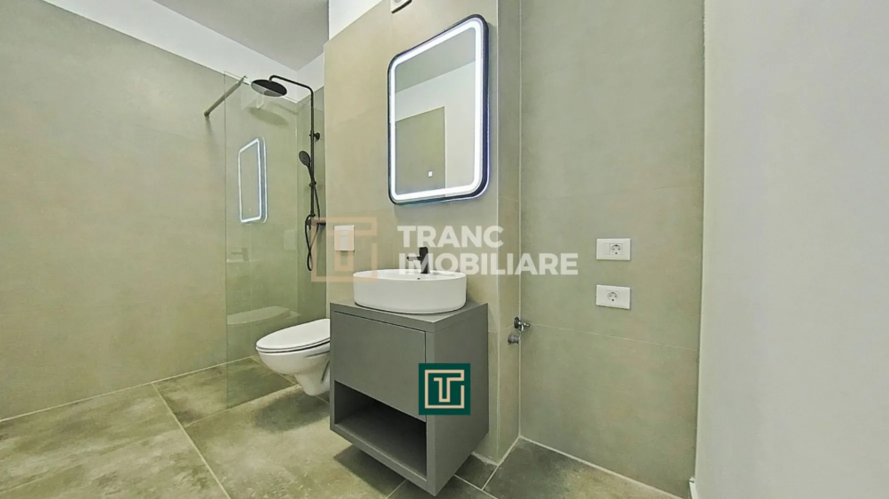 Apartament cu 2 camere într-un bloc nou, Via Carmina – Vladimirescu - Comisionul pentru cumpărător este 0%!

Îți prezentăm spre vânzare un apartament modern cu 2 camere, situat în cadrul proiectului rezidențial Via Carmina din Vladimirescu, una dintre cele mai apreciate zone rezidențiale din județul Arad. Amplasat într-un cartier liniștit, cu acces rapid către oraș și facilități moderne în apropiere, acest apartament este alegerea ideală pentru locuire sau investiție.

Imobilul a fost finalizat în anul 2024, iar apartamentul este poziționat la etajul 1 al unui bloc cu 3 etaje, dotat cu lift. Locuința are o suprafață utilă de aproximativ 53 mp și o suprafață construită de 64 mp, fiind compartimentată semidecomandat: dormitor, living, bucătărie, baie. Bucătăria open-space, integrată armonios cu zona de zi, oferă un spațiu luminos și funcțional, perfect pentru confortul zilnic.

Apartamentul beneficiază de finisaje premium, precum parchet, gresie și vopsea lavabilă de calitate superioară. Confortul termic este asigurat de centrala termică proprie pe gaz și sistemul de încălzire prin pardoseală, iar pentru siguranță și eficiență energetică imobilul este bine izolat și dotat cu videointerfon. Locuința se predă cu bucătăria complet mobilată și utilată, aer condiționat cu accesare la distanță și centrală pe gaz.

Zona este complet amenajată, cu drumuri asfaltate și iluminat stradal, oferind un cadru sigur și plăcut. Prețul nu include TVA 21% și locul de parcare.