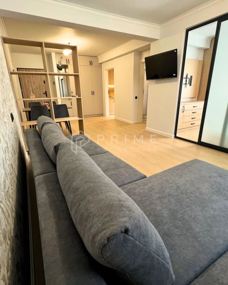 Apartament Premium 2 Camere | Zonă Semicentrală | Parcare - Amplasat într-o zonă semicentrală foarte bună, apartamentul oferă acces rapid către toate punctele de interes: magazine, farmacii, școli, grădinițe, parcuri și stații de transport în comun. Aveți tot ce vă trebuie la câteva minute distanță, fără a renunța la liniștea și confortul de acasă.

Compartimentare & Design Interior:
Interiorul impresionează printr-un design modern și armonios, în nuanțe neutre deschise, completate de textura caldă a lemnului și accente elegante de gri deschis. Materialele sunt de calitate superioară, iar mobilierul este nou, ales cu atenție pentru un ambient rafinat.

Livingul: Luminos, creează un spațiu aerisit și primitor.

Bucătăria: Separată, complet mobilată și utilată – perfectă pentru cei care preferă un spațiu distinct pentru gătit.
Dormitorul: Intim și relaxant, dotat cu pat matrimonial, noptiere moderne și aplice cu lumină ambientală pentru un plus de confort și stil.
Baia: Finisată cu foarte mult bun gust, dispune de plăci ceramice care imită lemnul în zona chiuvetei și a dușului, oferind un efect vizual cald și sofisticat.
Balcon: Atât livingul, cât și bucătăria au ieșire directă pe balcon.

Confort & Beneficii incluse:
Eficiență termică: Sistem de încălzire prin pardoseală, asigurând un confort uniform și costuri optimizate.
Dotări: Electrocasnice moderne și mobilier nou, de înaltă calitate.

Parcare securizată: Loc de parcare inclus în curtea interioară a imobilului, dotată cu poartă automatizată.

Condiții de închiriere:
Preț chirie: 550 Euro / lună.
Loc de parcare: inclus în preț.
Garanție: Contravaloarea a 2 luni de chirie.

Comision agenție: 50% din prima lună de chirie.

Un apartament ideal, cu acces facil către tot ce contează. Pentru detalii suplimentare și programarea unei vizionări, vă invităm să ne contactați!