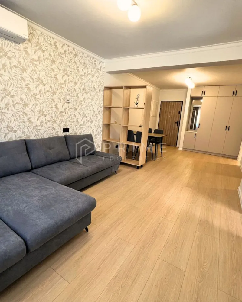 Apartament Premium 2 Camere | Zonă Semicentrală | Parcare - Amplasat într-o zonă semicentrală foarte bună, apartamentul oferă acces rapid către toate punctele de interes: magazine, farmacii, școli, grădinițe, parcuri și stații de transport în comun. Aveți tot ce vă trebuie la câteva minute distanță, fără a renunța la liniștea și confortul de acasă.

Compartimentare & Design Interior:
Interiorul impresionează printr-un design modern și armonios, în nuanțe neutre deschise, completate de textura caldă a lemnului și accente elegante de gri deschis. Materialele sunt de calitate superioară, iar mobilierul este nou, ales cu atenție pentru un ambient rafinat.

Livingul: Luminos, creează un spațiu aerisit și primitor.

Bucătăria: Separată, complet mobilată și utilată – perfectă pentru cei care preferă un spațiu distinct pentru gătit.
Dormitorul: Intim și relaxant, dotat cu pat matrimonial, noptiere moderne și aplice cu lumină ambientală pentru un plus de confort și stil.
Baia: Finisată cu foarte mult bun gust, dispune de plăci ceramice care imită lemnul în zona chiuvetei și a dușului, oferind un efect vizual cald și sofisticat.
Balcon: Atât livingul, cât și bucătăria au ieșire directă pe balcon.

Confort & Beneficii incluse:
Eficiență termică: Sistem de încălzire prin pardoseală, asigurând un confort uniform și costuri optimizate.
Dotări: Electrocasnice moderne și mobilier nou, de înaltă calitate.

Parcare securizată: Loc de parcare inclus în curtea interioară a imobilului, dotată cu poartă automatizată.

Condiții de închiriere:
Preț chirie: 550 Euro / lună.
Loc de parcare: inclus în preț.
Garanție: Contravaloarea a 2 luni de chirie.

Comision agenție: 50% din prima lună de chirie.

Un apartament ideal, cu acces facil către tot ce contează. Pentru detalii suplimentare și programarea unei vizionări, vă invităm să ne contactați!