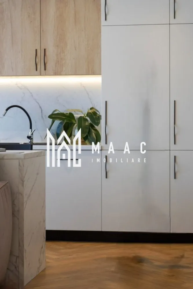 Apartament Premium | 3 camere | Balcon | Garaj subteran | Turnișor - MAAC vă propune spre închiriere un apartament premium cu 3 camere, conceput într-un stil minimalist și funcțional, unde confortul, eleganța și atenția la detalii se îmbină perfect pentru a oferi un spațiu ideal de locuit.

Apartamentul dispune de un living generos cu bucătărie open-space, amenajată modern și echipată cu hotă puternică cu evacuare exterioară, perfectă pentru un plus de confort și eficiență. Zona de zi este completată de o canapea extensibilă, ideală atât pentru relaxare, cât și pentru oaspeți.

Locuința beneficiază de două dormitoare luminoase, două băi finisate premium și mobilier realizat integral la comandă, inclusiv saltelele, pentru un nivel ridicat de confort și un design unitar, modern și rafinat.

Încălzirea se realizează prin pardoseală, cu centrală proprie și termostat individual în fiecare cameră, inclusiv în băi, oferind un control optim al temperaturii și eficiență energetică. Orientarea sud-estică asigură lumină naturală pe tot parcursul zilei.

Unul dintre punctele forte ale proprietății este balconul generos de 10 mp, care poate fi amenajat în funcție de nevoile și preferințele viitorului chiriaș. Proprietarii sunt deschiși la sugestii pentru a transforma experiența locuirii într-una cât mai plăcută.

Apartamentul beneficiază și de loc de parcare în garajul subteran, iar accesul se face într-un ansamblu rezidențial modern și liniștit, cu multă zonă verde, pomi fructiferi, loc de joacă pentru copii, zonă de fitness, spații de relaxare, zonă de grătar și fire pit.

În plus, proprietatea are ieșire către o curte interioară amenajată cu zonă de fructe și legume, flori, arbuști decorativi și spațiu de relaxare, unde se poate oferi acces, dacă se dorește.

Poziționarea este excelentă, într-o zonă liniștită, cu acces facil către magazine precum Profi și Trans Agape, stații de autobuz, zona industrială și aeroport, aflate la aproximativ 5 minute cu mașina, iar centrul orașului și Piața Mare se află la doar 15 minute distanță.

Un apartament ideal pentru cei care își doresc un stil de viață modern, confortabil și echilibrat, într-un cadru verde și liniștit.

Pentru mai multe detalii și vizionări, vă rugăm să menționați ID : CP3081929