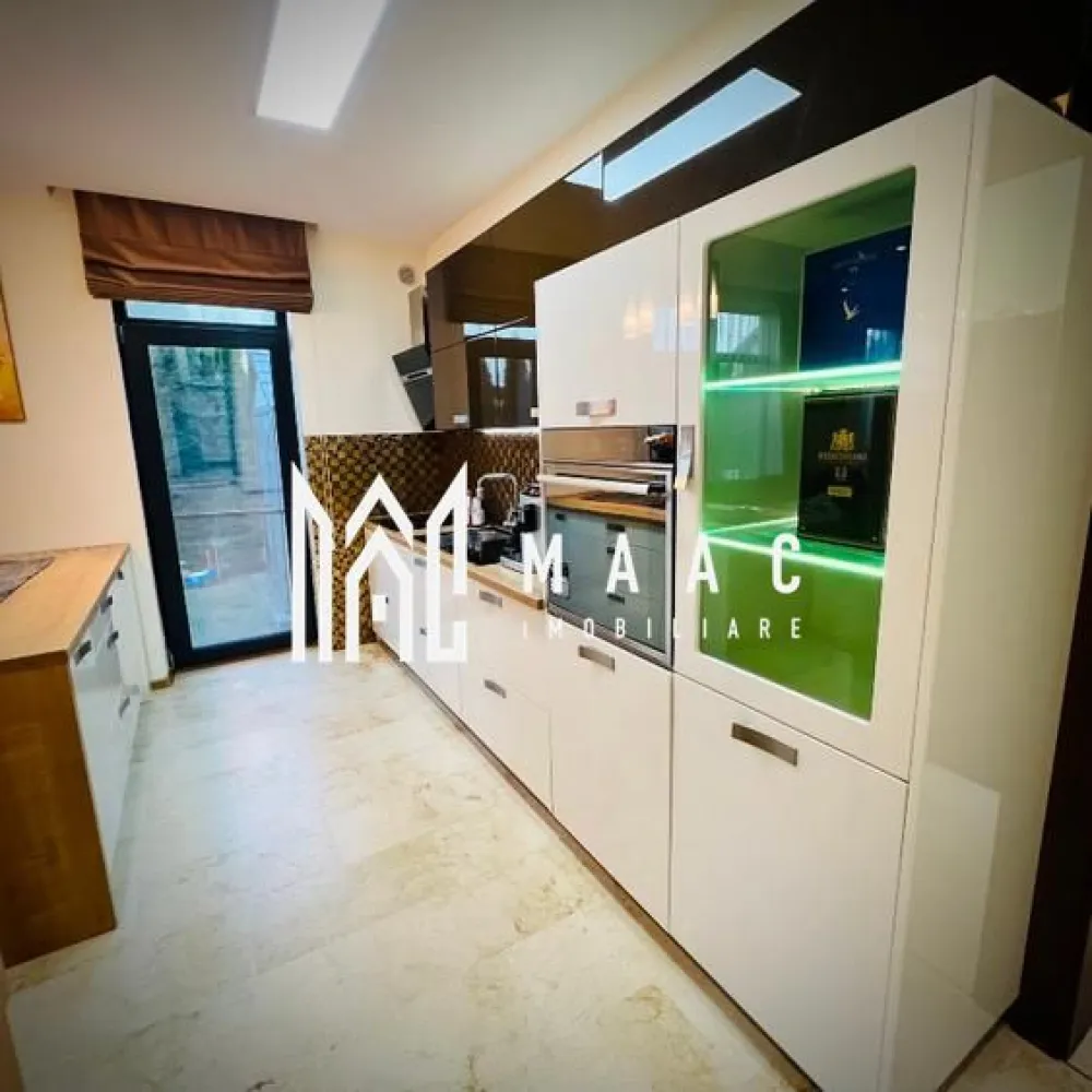 Casă 4 camere | 135mp utili + terasă 55 mp | Curte 180mp - MAAC Imobiliare vă propune spre vânzare o casă modernă și elegantă, situată în Șelimbăr, într-o zonă liniștită, cu acces rapid către Shopping City Sibiu, parcuri și zone de recreere, grădinițe, școli și transport în comun, ideală pentru o familie care își dorește confort și funcționalitate într-un cadru rezidențial bine cotat.

Proprietatea are o suprafață utilă de 134,5 mp, terasă panoramică de 55 mp la etaj retras, teren de 249,5 mp și o curte liberă de aproximativ 180 mp.

Compartimentare:

Parter:
-living generos, cu aer elegant
-bucătărie open-space
-bucătărie închisă, complet utilată
-baie de serviciu
-acces direct către curte

Etaj:
-3 dormitoare spațioase, mobilate modern
-baie mare cu jacuzzi

Etaj retras:
-baie cu duș
-spațiu pentru mașină de spălat rufe
-terasă panoramică de 55 mp

Dotări și finisaje:
-mobilier premium la comandă
-canapele Mobexpert și Divani & Sofa
-tavane cu spoturi și iluminat LED ambiental
-marmură la parter, în hol, bucătării și baie de serviciu
-lemn natural în living
-scară din lemn masiv cu balustradă din fier forjat decorativ
-tâmplărie QFORT tripan
-centrală termică Viessmann
-instalații electrice Schneider

Exterior și facilități:
-curte amenajată cu gazon, plante decorative și gard viu din tuia
-sistem automat de irigații pentru gazon și flori
-poartă de acces și poartă de garaj automatizate cu telecomandă
-două locuri de parcare în curte
-căsuță de grădină pentru depozitare

Locuința se predă complet mobilată și utilată, în stare excelentă, reprezentând o opțiune potrivită pentru cei care caută o casă modernă în Șelimbăr, aproape de facilitățile urbane din Sibiu.

Pentru mai multe detalii sau programarea unei vizionări vă rugăm să menționați la telefon numărul CP2676807.