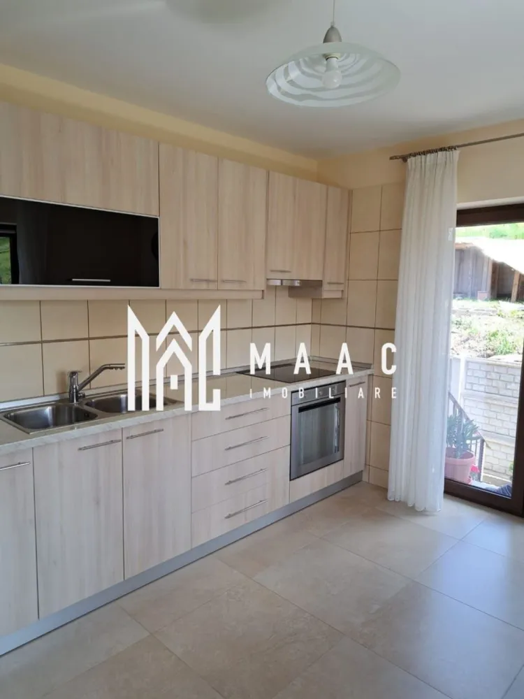 Casă individuală | 184 MPU | Teren 500MP | Șura Mare - MAAC Imobiliare vă propune spre vânzare o casă individuală modernă, cu 5 camere, situată în Șura Mare, la doar câteva minute de Sibiu, într-o zonă liniștită, ideală pentru familie.

Proprietatea dispune de o suprafață utilă de 184 mp și este amplasată pe un teren generos de 500 mp, oferind spațiu, confort și intimitate.

Compartimentare:
Demisol:
Garaj spațios
Cameră multifuncțională
Camera centralei
Pivniță
Baie de serviciu

Parter:
Living luminos
3 dormitoare
Bucătărie separată
Hol
Baie

Locuința beneficiază de sistem de încălzire pe gaz sau pe peleți, oferind flexibilitate și eficiență energetică.

Exteriorul este amenajat cu zonă verde, pomi fructiferi și curte pavată, ideală pentru relaxare sau petrecerea timpului în aer liber. Strada este în curs de asfaltare, cu termen estimat de finalizare în 2–3 luni, ceea ce va aduce un plus de confort și valoare proprietății.

Casa se vinde complet mobilată și utilată și poate fi predată imediat.

Pentru mai multe detalii sau pentru programarea unei vizionări, vă rugăm să ne contactați.
Specificați ID-ul CP2926583.