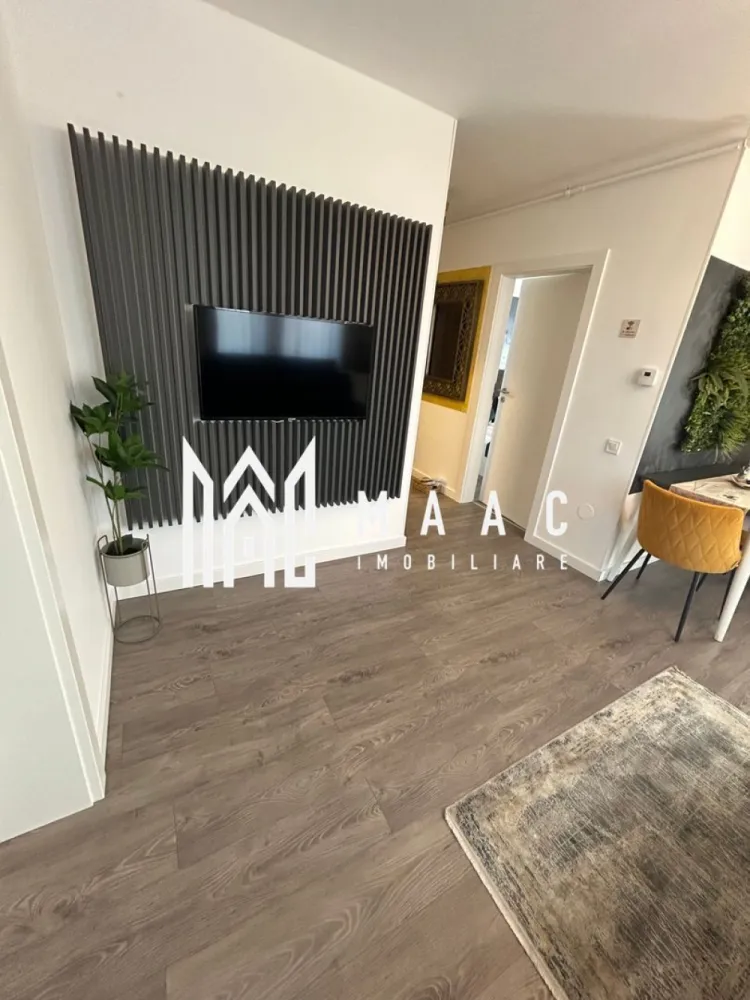 Apartament Modern 2 Camere I Incălzire Pardoseală I Parcare I Sibiu - MAAC Imobiliare vă prezintă spre vânzare un apartament modern cu 2 camere, situat în cartierul Henri Coandă din Sibiu, o zonă rezidențială în plină dezvoltare, apreciată pentru liniște, accesibilitate și comunitatea în formare.

Apartamentul este amenajat la standarde premium și se vinde complet mobilat și utilat, fiind ideal atât pentru locuire personală, cât și pentru investiție.
Locuința oferă confort modern și funcționalitate, fiind pregătită pentru mutare imediată sau pentru introducerea în circuitul de închiriere.

Dotări și beneficii
Incălzire în pardoseală
Aer condiționat
Bucătărie complet utilată (plită electrică, frigider și electrocasnice)
Televizoare în fiecare cameră
Mobilier modern de calitate superioară
Loc de parcare inclus
Interiorul apartamentului este amenajat într-un stil modern și elegant, cu atenție la detalii și materiale de calitate, oferind un spațiu confortabil și primitor.

Datorită poziționării și dotărilor, proprietatea este potrivită pentru:
Inchiriere pe termen lung
Regim hotelier
Locuință personală

Apartamentul reprezintă o oportunitate excelentă pentru cei care caută o locuință modernă sau o investiție sigură într-o zonă în dezvoltare din Sibiu.

Bonus: Primele apartamente vândute vor beneficia de spațiu de depozitare la subsol, ideal pentru depozitarea obiectelor personale sau sezoniere.
Proprietățile bine amenajate din această zonă se vând rapid. Recomandăm programarea unei vizionări din timp.

Pentru mai multe informații și programări la vizionare, vă rugăm să menționați ID anunț: CP2956611