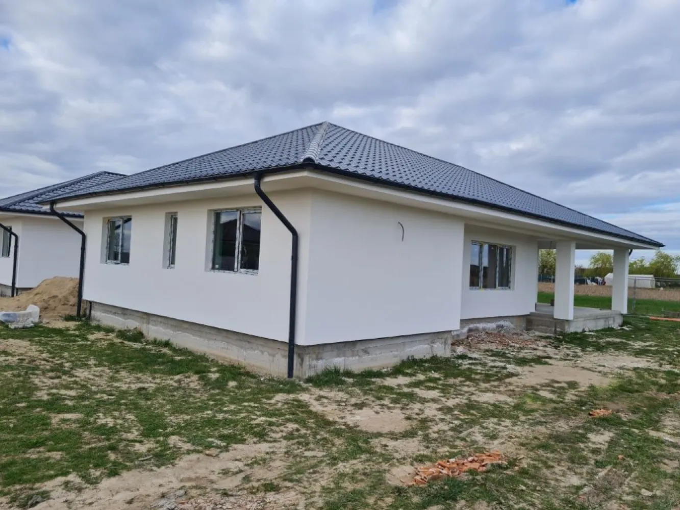 BRASADAS vinde casa noua, parter, zona Cionchesti - Agenția imobiliara BRASADAS vinde case de locuit Parter situate in loc. Cionchesti intr-o zona linistita, foarte cautata in ultima vreme, in cartier nou de case. Locatia este aproape de soseaua de centura a orasului Satu Mare, fiind foarte usor accesibila. Casele dispun de 600 mp teren fiecare, sunt optimizate functional astfel incat sa raspunda si celor mai exigente cerinte. Cu o suprafata construita de 125,00 mp la care se adauga o terasa generoasa de aproape 20 mp, planimetria este compusa dintr-o zona de zi cu living, bucatarie, camara, doua dormitoare cu baie care sa le deserveasca si separat cu acces spre terasa un dormitor matrimonial si cea de-a doua baie. Cu acces din exterior casa dispune de incapere separata pentru centrala termica. Pretul afisat este pentru stadiul la "semi-finisat" Imobilul se preda la stadiul de finisat in exterior si semifinisat in interior (realizat 1 strat glet si sapa de beton) pentru pretul de 83.500 euro Descriere constructiva: - Fundatii continue din beton armat, - Structura din zidarie portanta realizata din caramida cu goluri verticale, termoizolanta, confinata cu elemente de beton armat cu rol antiseismic - Sarpanta de lemn, ignifugata, invelitoare din tigla metalica - Izolatii termice exterioare cu polistiren Austrotherm anti foc EPS80 + extrudat XPS in zona golurilor pentru ferestre si usi - Izolatii termice in zona de pod cu vata minerala 15 cm grosime, si polistiren extrudat la pardoseala de sub cota +/-0.00 - Incalzire in pardoseala - Tamplarie din PVC Rehau cu geam termoizolant, colorate (int+ext) aspect gri antracit. Lucrarile de executie sunt bine documentante inclusiv cu fotografii, respectand cu strictete normativele romanesti si europene privind executia cladirilor.